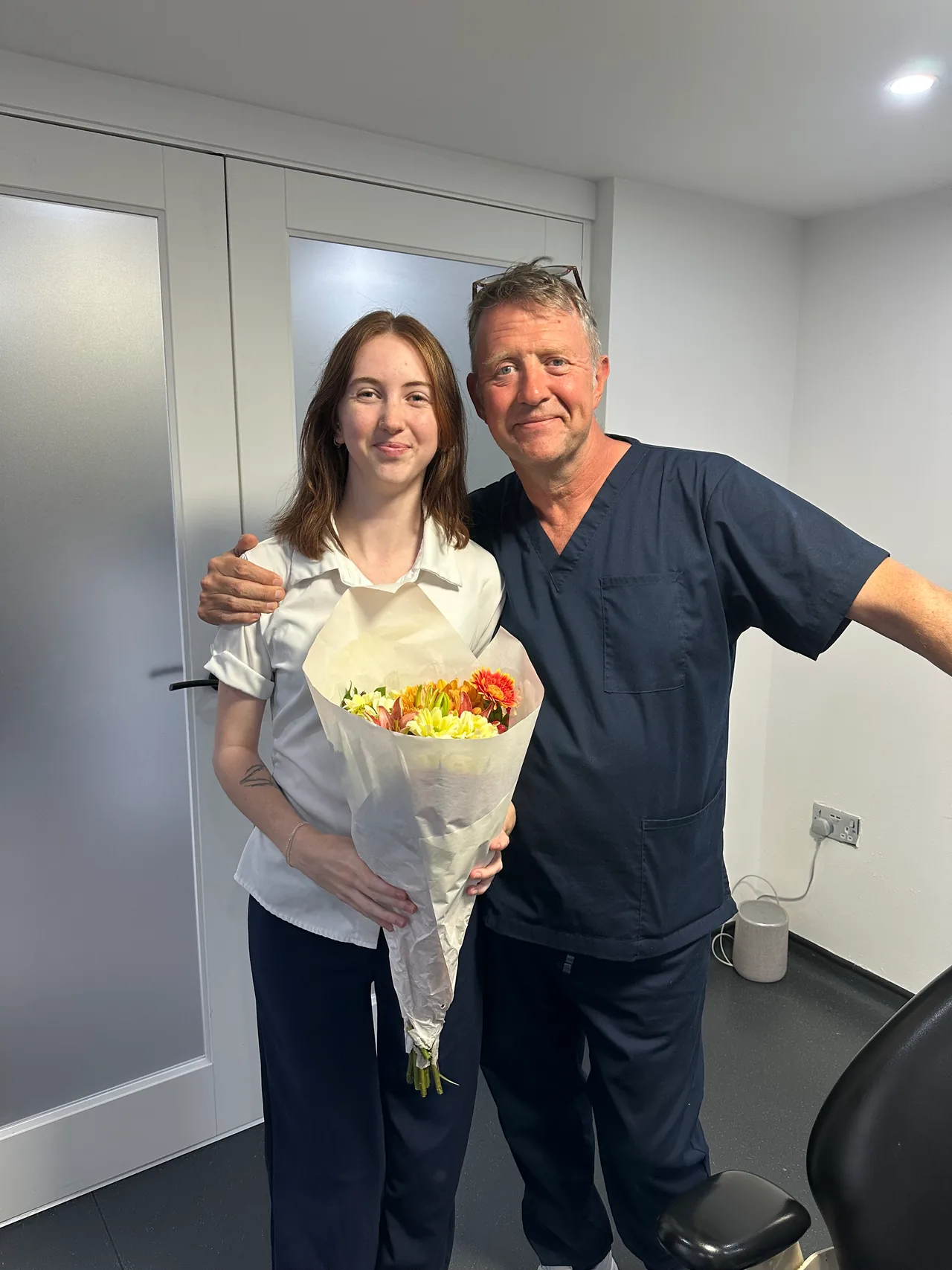 Simon and Georgie at the clinic holding a bouquet of flowers